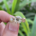 Three stone Old Mine Cut moissanite ring rotating view showcasing champagne side stones and vintage design