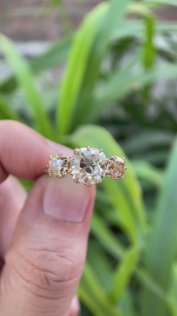 Three stone Old Mine Cut moissanite ring rotating view showcasing champagne side stones and vintage design