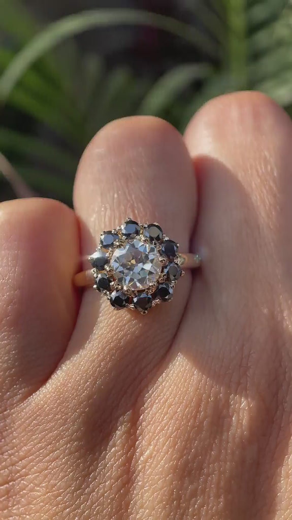 Hand worn vintage halo moissanite ring with black accent stones showing sparkle, contrast, and side profile in natural lighting