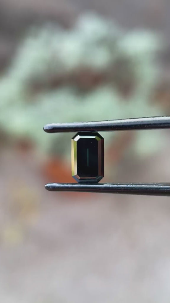 Black green emerald cut moissanite step cut Old Mine rotating view showing deep color and reflective facets