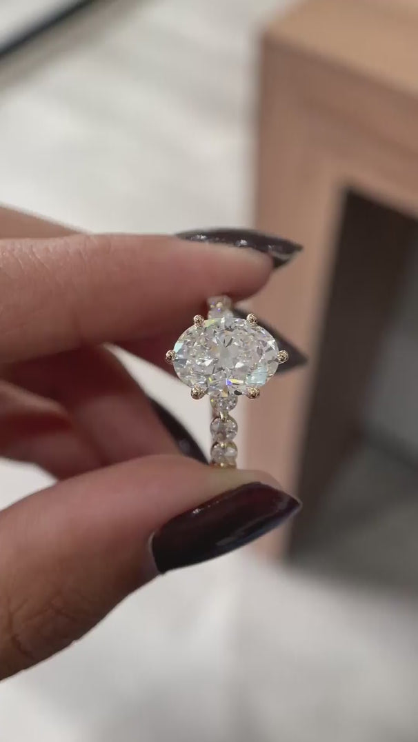 Close rotating view oval lab diamond ring with round side stones in yellow gold