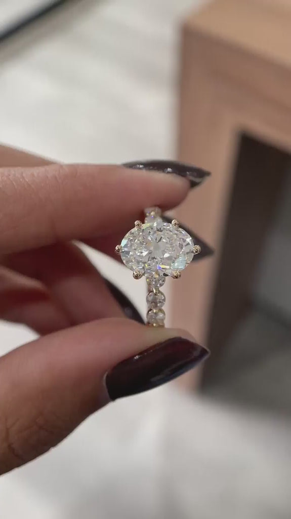 Close rotating view oval lab diamond ring with round side stones in yellow gold